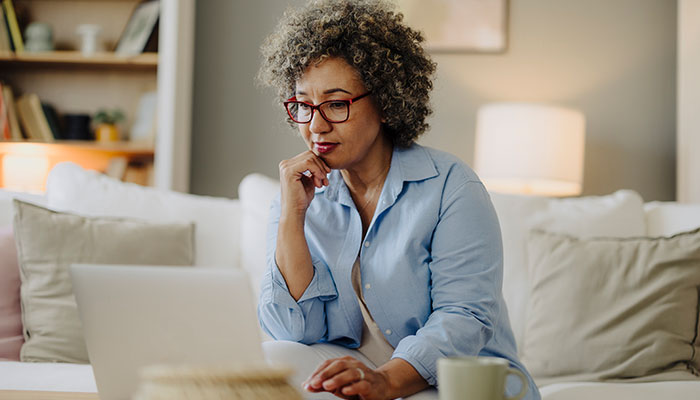 African American women reviewing her budget on a laptop in her home.