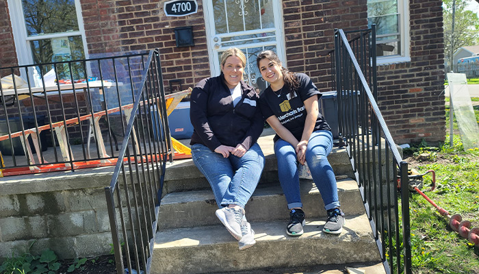 First Merchants Team Members working sitting on the front stairs of the home.