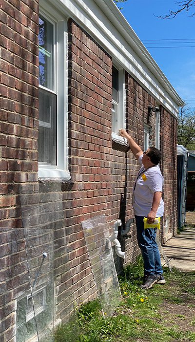 First Merchants Team Member working on sealing a window from outside..
