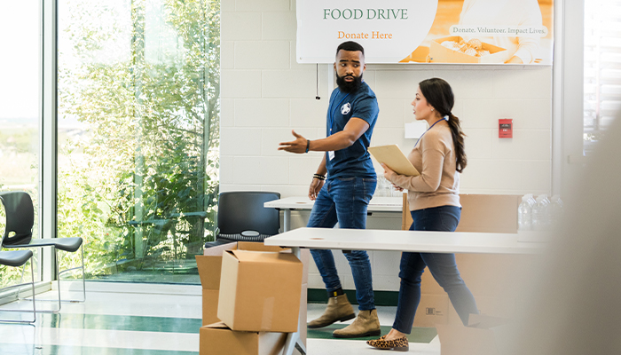 Male and female walking through a office setting up for a food drive