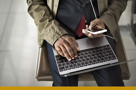 Picture of person holding smart phone and working on laptop